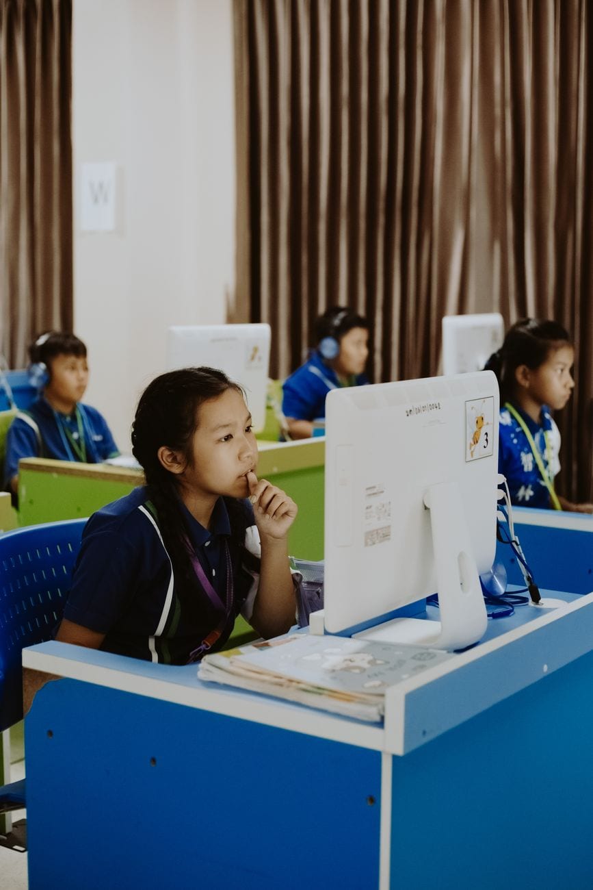 Students focused on computer studies in an educational environment, wearing headphones.