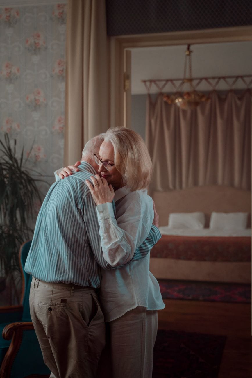 Warm embrace between elderly couple in a cozy home, showcasing love and togetherness.