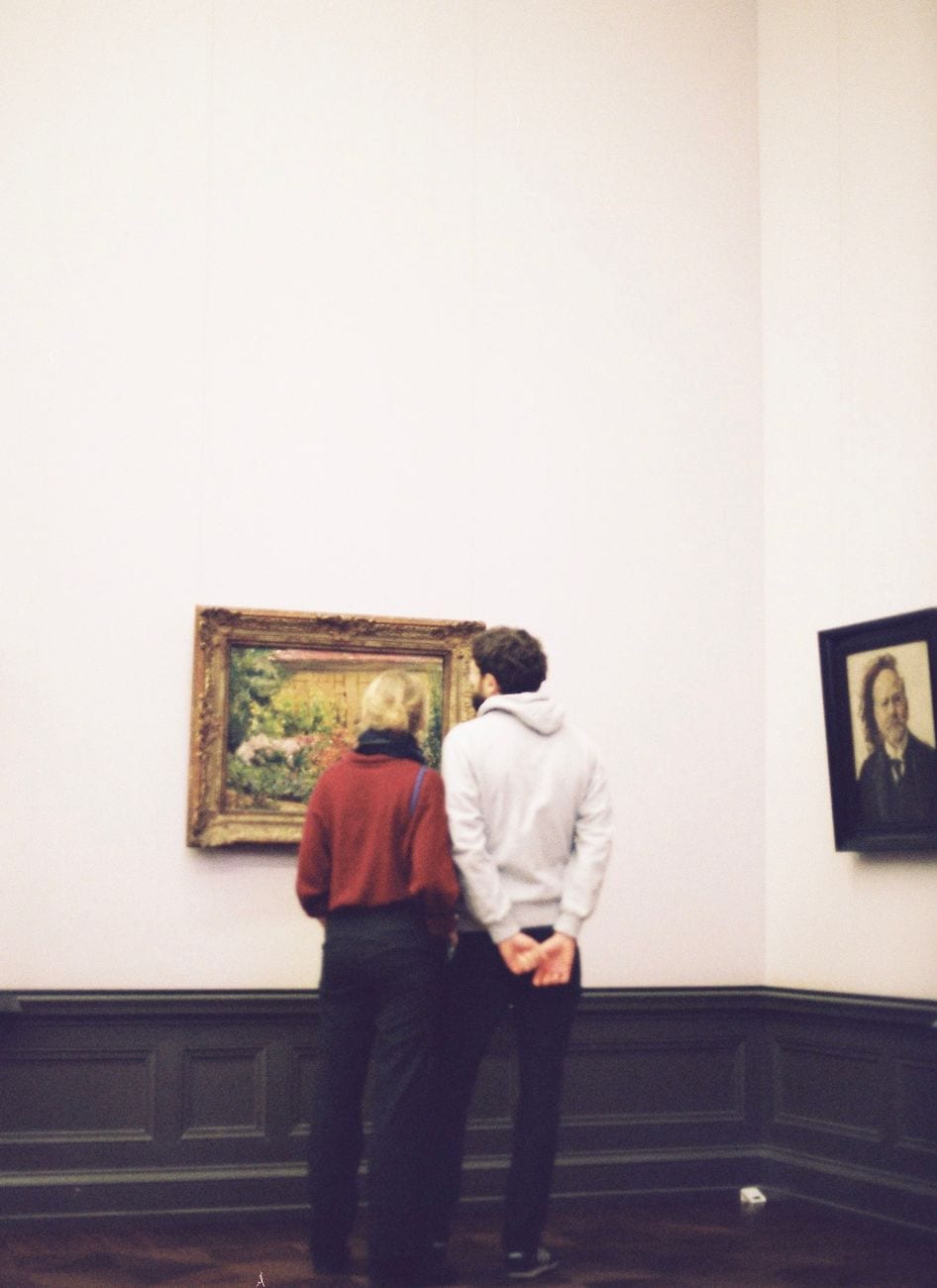A couple observes artwork in a serene museum environment, capturing a moment of cultural appreciation.